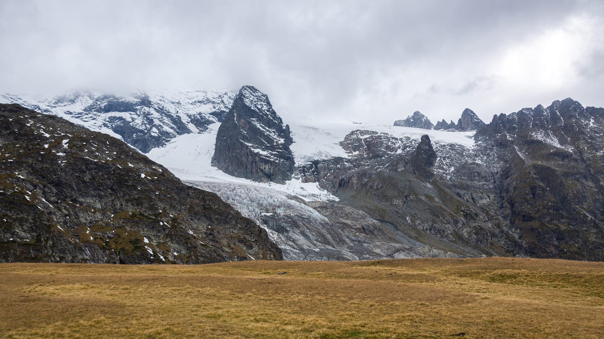 a glacier rises in the background in the Russian Caucasus, the sky heavy with fog