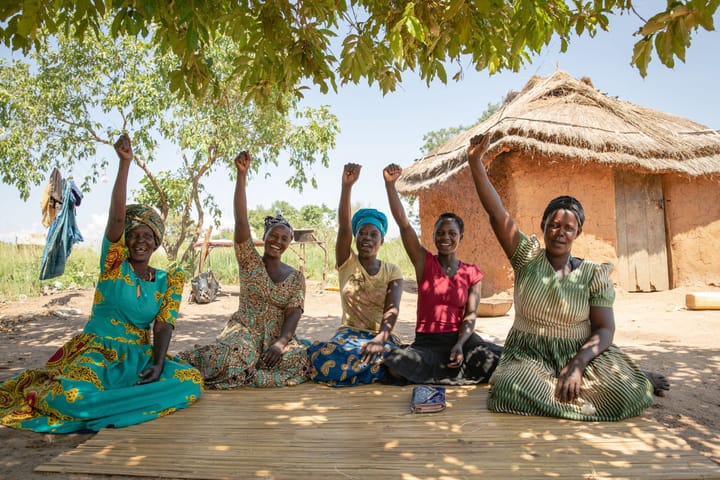 five African women sitting with fists raised